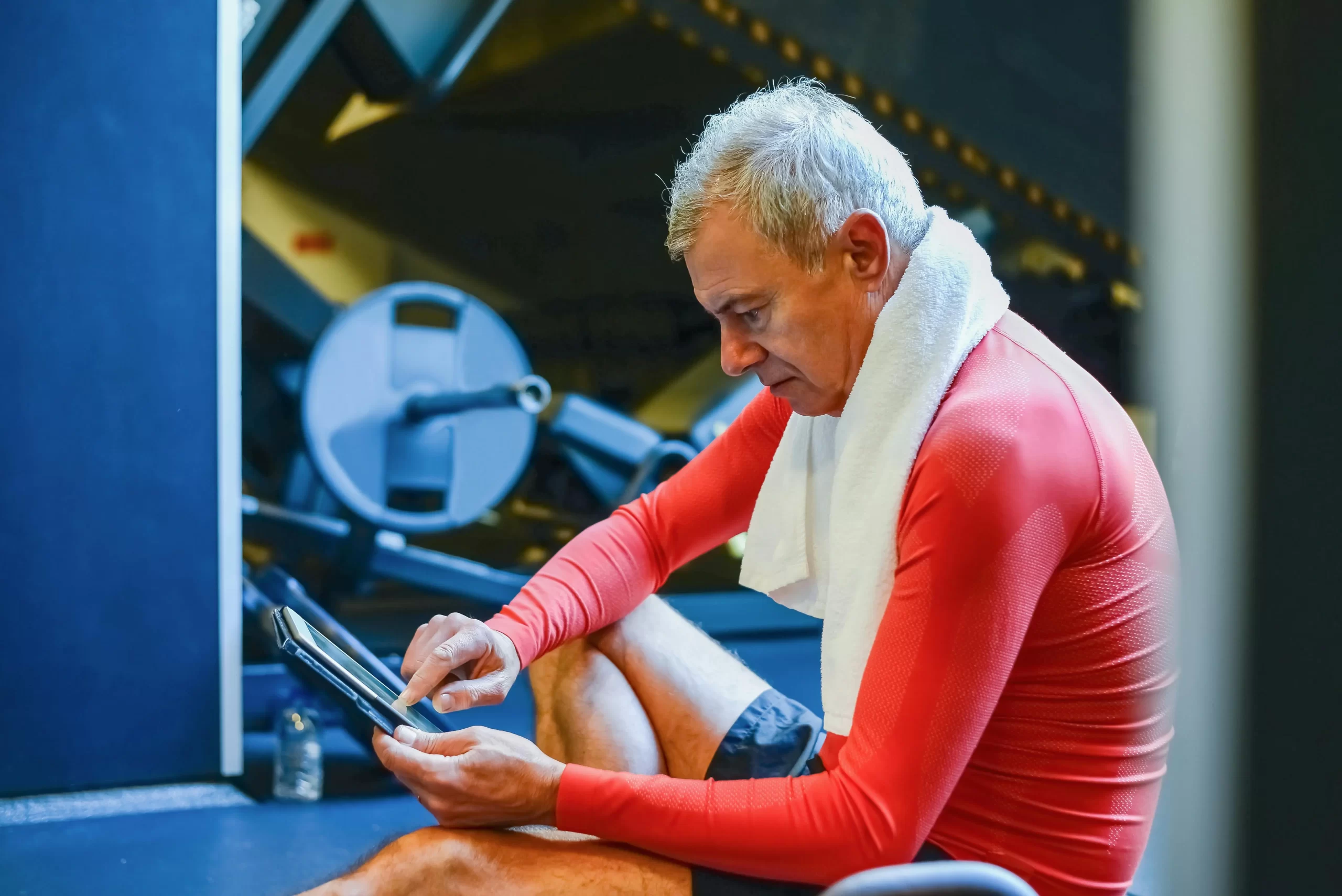 old person over 40 working out and checking a program in the gym